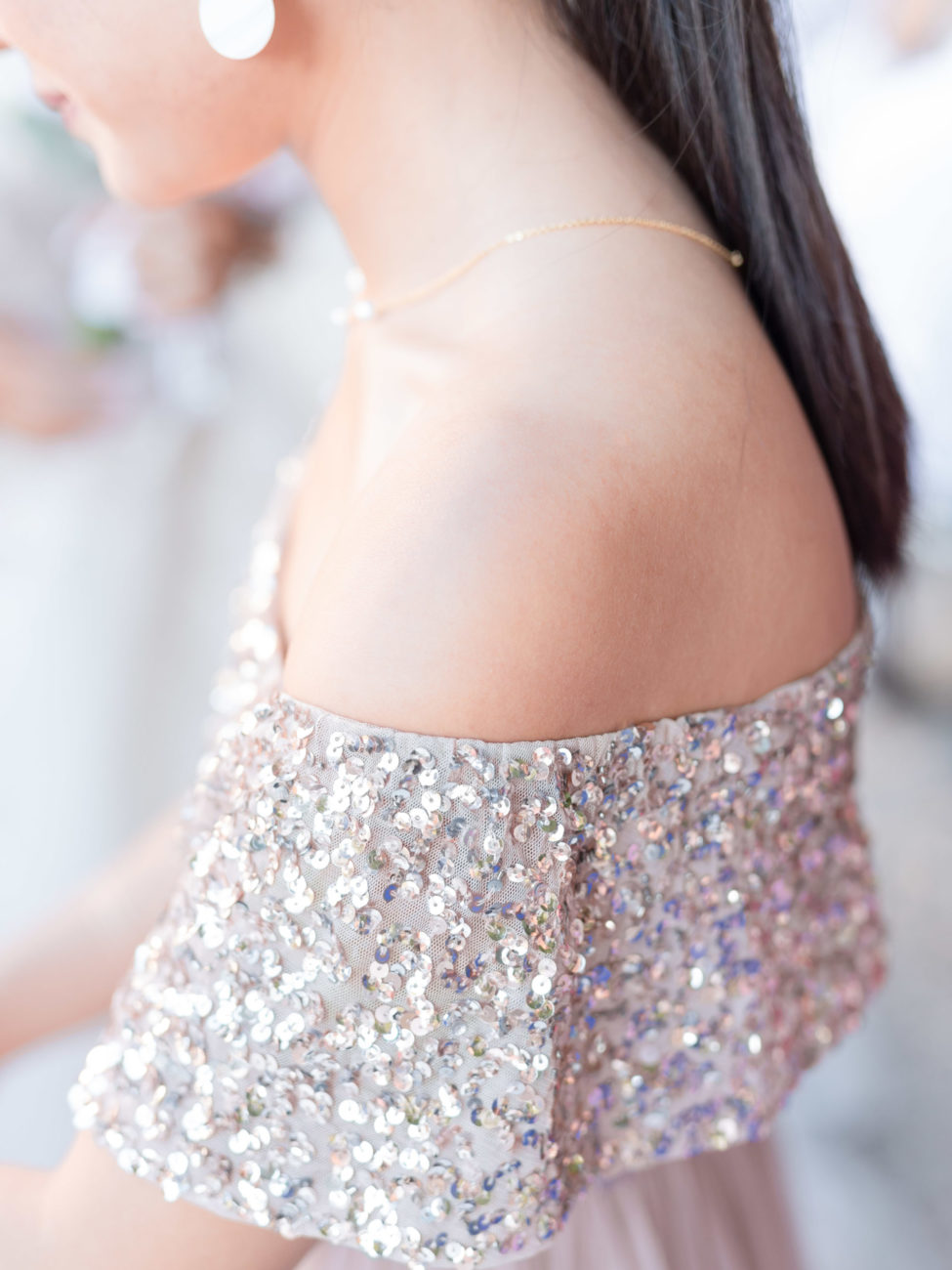 Détail de l'épaule et de la robe d'une invitée lors d'un mariage au Château de Santeny