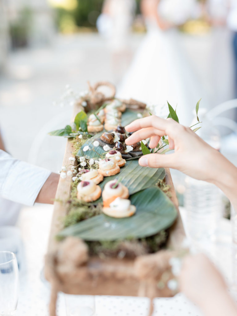 Un vin d'honneur raffiné lors d'un mariage au château de Santeny, une main saisait un amuse-bouche